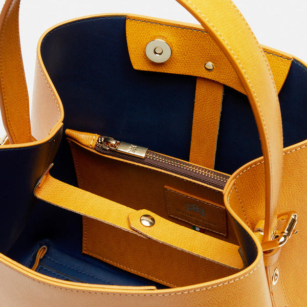 Un Secchiello Della Collezione Alice di colore Giallo sobrio ed elegante. Caratterizzato da uno spallaccio regolabile in altezza, chiusura a bottone e tasca a chiusura zip interna.